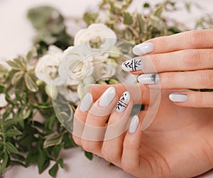 Gentle neat manicure on female hands on flowers background. Nail design