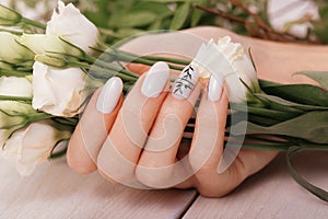 Gentle neat manicure on female hands on flowers background. Nail design