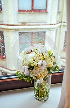 Gentle peony and cotton bouqet on the rainy window