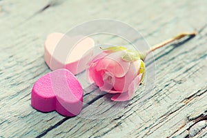 Gentle pink rose and heart on wooden table.