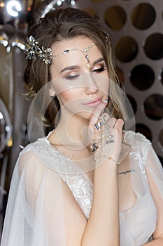 Gentle portrait of a beautiful cute happy bride with a beautiful hairdo festive bright make-up in a wedding dress with earrings an
