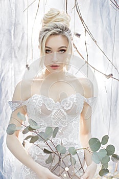 Gentle portrait of a beautiful cute happy bride with a beautiful hairdo festive bright make-up in a wedding dress with earrings an