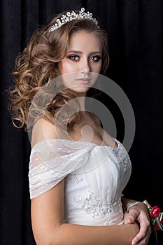 Gentle portrait of a beautiful cute happy bride with a beautiful hairdo festive bright make-up in a wedding dress with earrings an