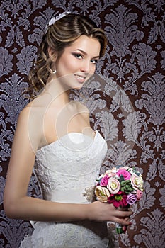 Gentle portrait of happy smiling beautiful girls in white wedding dress with a wedding bouquet in hand with beautiful hair