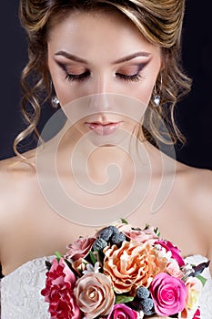 Gentle portrait of happy smiling beautiful girls in white wedding dress with a wedding bouquet in hand with beautiful hair