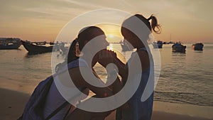 Gentle portrait of young mother with her little daughter on the beach at sunset.