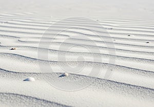 Gentle ripples of white sand stretch across the image, creating an undulating pattern. The sand is