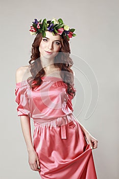 Gentle romantic appearance of the girl with a wreath of roses on her head and a pink dress. Joyful Jolly spring woman. Summer lady