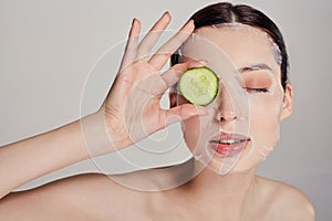 Gentle sophisticated calm girl in a moisturizing mask with a fresh cucumber