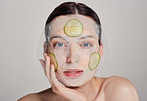 Gentle sophisticated girl in a moisturizing mask with a fresh cucumber on the face