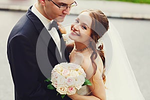 Gentle stylish sgroom and bride holding boucuet of creamy roses