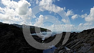 Gentle upward pan over coastal devonian rock rockpools