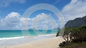 Gentle wave lap on Waimanalo Beach looking towards Rabbit island and Rock island on a nice day with clouds in the sky