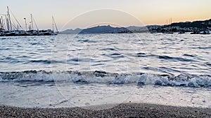 Gentle waves wash over a pebbly beach at twilight, summer holiday travel