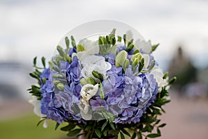 Gentle wedding bouquet of hydrangeas, roses and freesia on blurred wooden background. Wedding details in blue and white