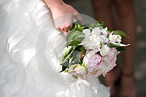 Gentle wedding bouquet with peonies in hands of the bride