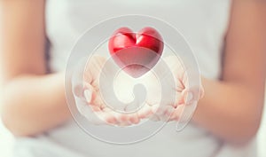 Gentle womens hands and a red heart glowing in his hands. Valentines mothers day and charity concept