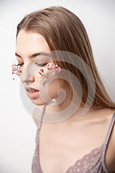 Gentle young woman in lingerie with flowers on face