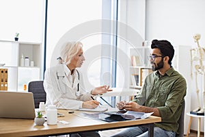 Gentleman describing symptoms of illness to senior female doctor.