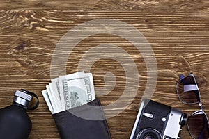 Gentlemanly set: sunglasses, perfume, wallet, money,camera on wooden background