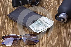 Gentlemanly set: sunglasses, perfume, wallet, money,camera on wooden background