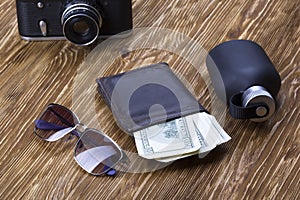 Gentlemanly set: sunglasses, perfume, wallet, money,camera on wooden background