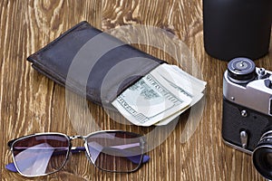 Gentlemanly set: sunglasses, perfume, wallet, money,camera on wooden background