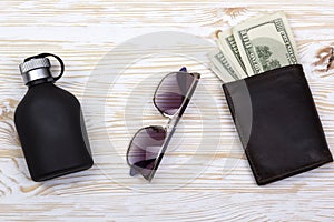 Gentlemanly set: sunglasses, perfume, wallet with money on wooden background