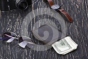 Gentlemanly set: sunglasses, wallet, camera, watch on wooden background