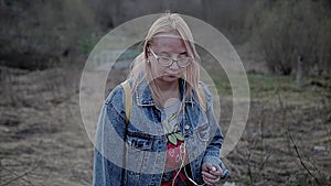 She gently walks along the path at the urban wasteland. In the background are trees and dry grass.