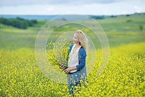 Genuine cute lady woman in meadow of yellow flowers sniffing flower bouquet. Attractive beautiful young girl enjoying the warm sum