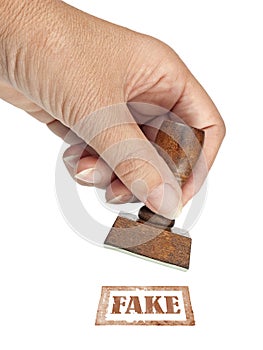 Genuine fake, rubber stamp. My hand with rubber stamp isolated on white. Business, politics or trade ethical concept.