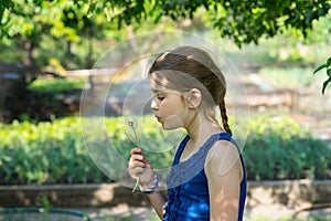 Genuine girl holding a fragile fuzzy dandelion