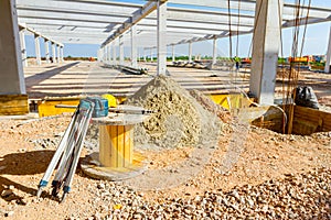 Geodesist equipment, tripod is placed next the wooden spool at building site