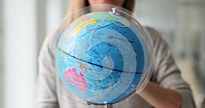 Geographical globe is rotated around axis woman hand