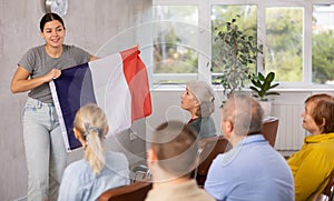 Geography lesson in university class - teacher talks about France, holding flag in his hands