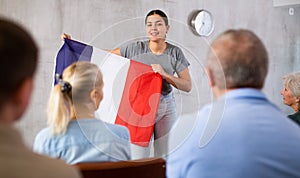 Geography lesson in university class - teacher talks about France, holding flag in his hands