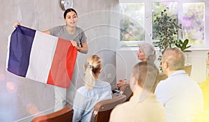 Geography lesson in university class - teacher talks about France, holding flag in his hands