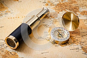 Geography, navigation and traveling concept with vintage compass, antique brass telescope or spyglass and old orange and brown map