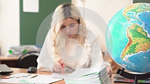 Geography teacher checks students' notebooks in class. School teacher at work