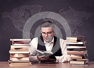 Geography teacher at desk with pile of books