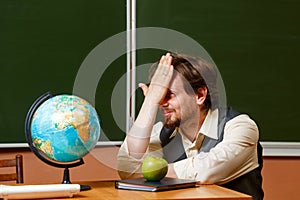 Geography teacher sits in front of a globe.