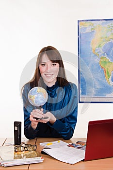 Geography teacher at the table with a globe in her hands