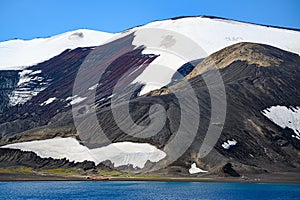 Geologic layers on volcanic mountains of Deception Island, Antarctica. Small sunken tanks of abandoned whale station, Lost places,