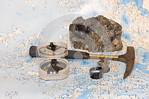 Geological fieldwork tools: hammer, compass, magnifying glass, rock samples, topographic and geological maps