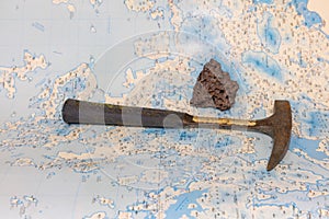 Geological fieldwork tools: hammer, compass, magnifying glass, rock samples, topographic and geological maps