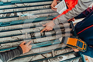 Geological gold core samples with team of mining workers measuring drilled rock top view. Selective focus