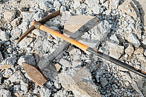 Geological pick with orange handle on the stones next to old hammer