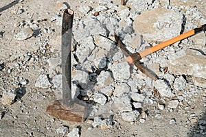 Geological pick with orange handle on the stones next to old hammer