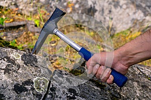 Geologist examines a mineralogical sample with the help of a geological hammer